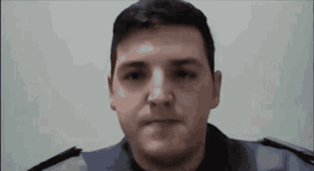 a man in a police uniform is looking at the camera and making a face .