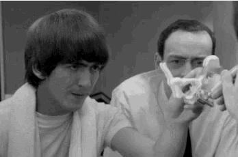 a black and white photo of two men looking at a model of a human skull .
