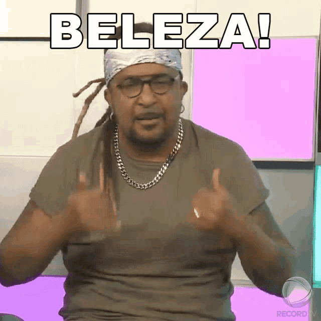a man with dreadlocks and glasses is giving a thumbs up and says beleza