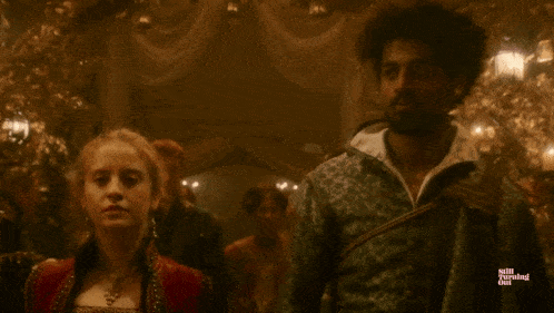 a man and a woman are standing in a dark room with the words mill turning girl visible
