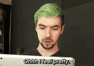 a man with green hair and a beard is looking at a tablet and saying `` ohhh i feel pretty '' .