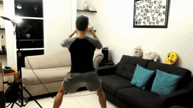 a man squatting in a living room with a couch