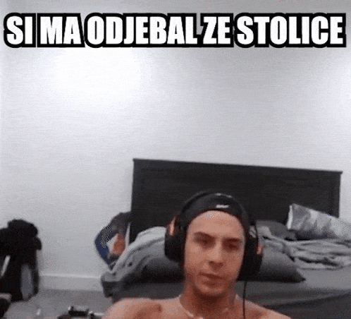 a shirtless man wearing headphones is sitting on a bed in a bedroom .