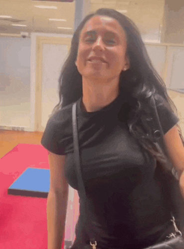 a woman in a black shirt is standing in a room with a purse .