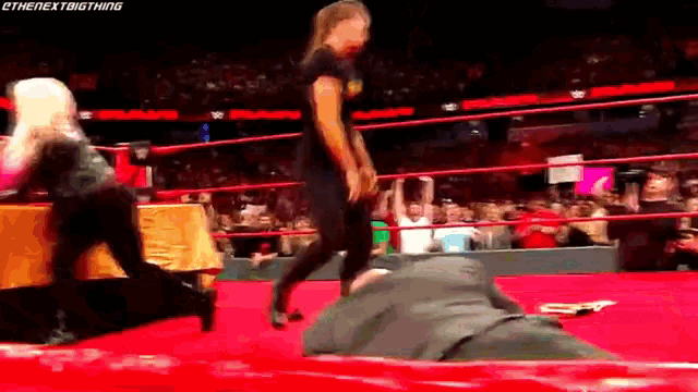 two women are wrestling in a wrestling ring with a crowd watching