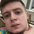 a young man is taking a selfie with his hand to his chin .