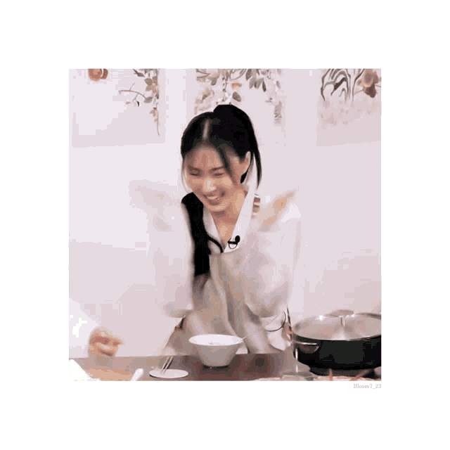 a woman is sitting at a table with a bowl of food and a pot