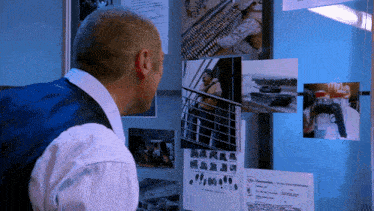 a man is looking at pictures on a wall and one of them says ' military intelligence ' on it