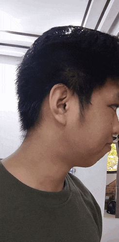 a close up of a man 's ear with a green shirt on