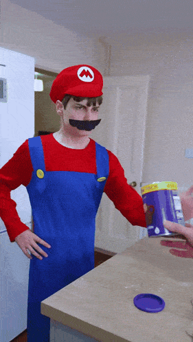 a man dressed in a mario costume holds a purple container