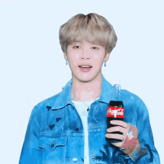 a young man in a blue denim jacket is holding a coca cola bottle