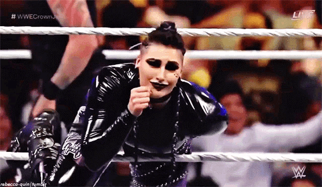 a woman in a wrestling ring is wearing a black and blue outfit