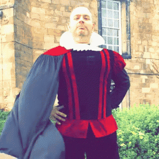 a man in a red and black costume is standing in front of a building