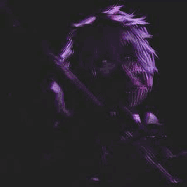 a man with purple hair is holding a gun in a dark room .