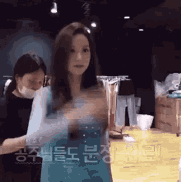 a woman in a blue dress is standing in a room with other women .