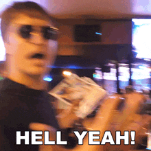 a man wearing sunglasses is holding a box of money and says hell yeah