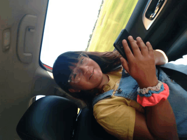 a girl wearing glasses is sitting in the back seat of a car