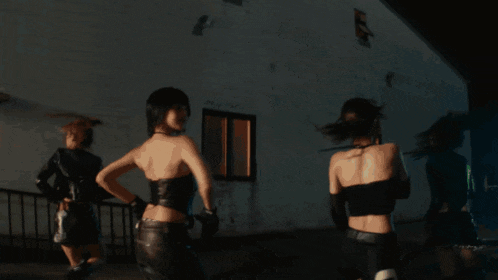 a group of women are dancing in a dark room