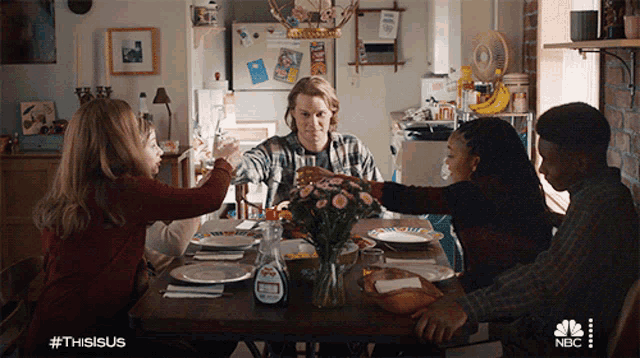 a group of people are sitting at a table with a bottle of syrup on it
