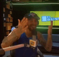 a man wearing headphones and a hat is giving the middle finger in front of a screen that says el buini
