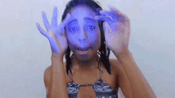 a woman in a bikini is covering her face with her hands and making a funny face .