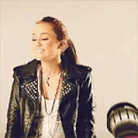 a woman wearing a leather jacket and a necklace is smiling