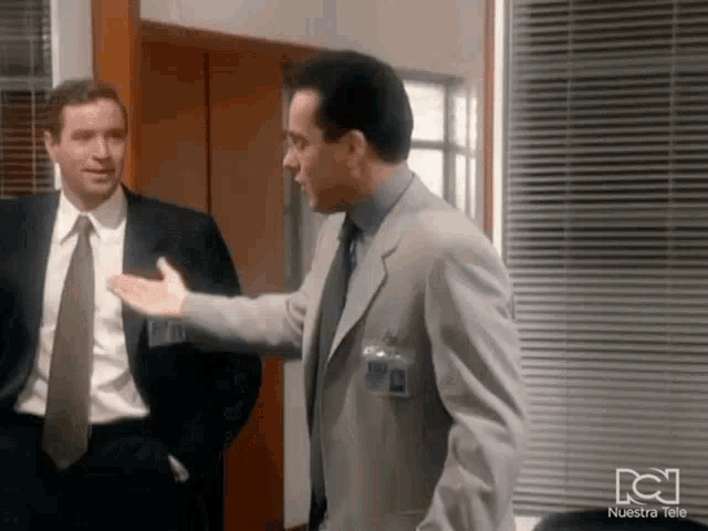 two men in suits and ties are standing next to each other with nuestra tele written on the bottom right corner