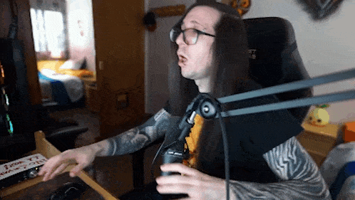 a man with long hair and tattoos is sitting in front of a microphone