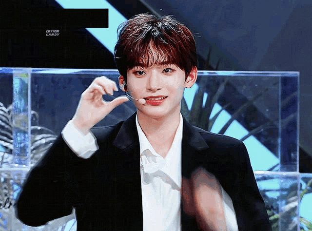 a young man wearing a black jacket and a white shirt is holding a microphone in his hand