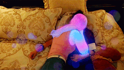 a man and a woman are hugging on a bed with glow in the dark lights projected on them
