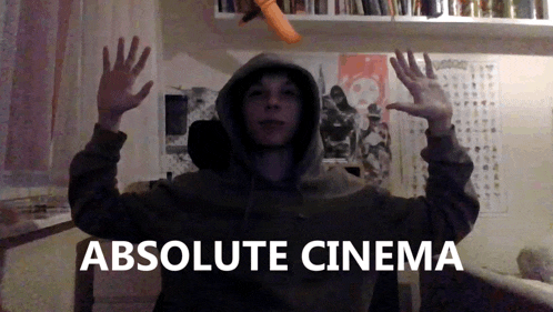 a man in a hoodie stands in front of a sign that says " absolute cinema "