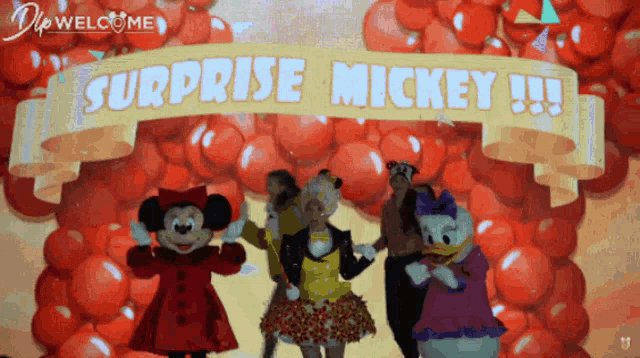 mickey mouse and daisy duck are standing in front of a surprise mickey sign