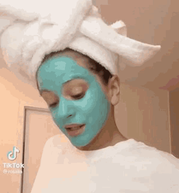 a woman wearing a blue face mask with a towel wrapped around her head .