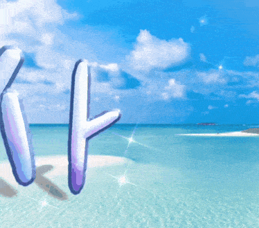 the letters t and t are on a beach with the ocean in the background