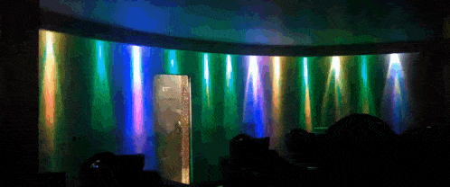 a dark room with a rainbow of lights coming out of a door