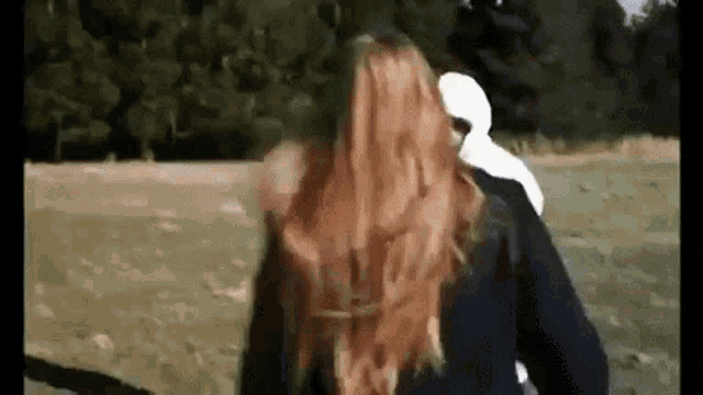 a woman with long red hair is standing next to a man in a white hoodie .