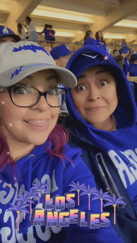 two women wearing blue los angeles sweatshirts are posing for a picture