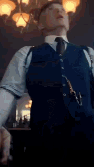 a man in a suit and tie is standing in a dark room holding a gun .