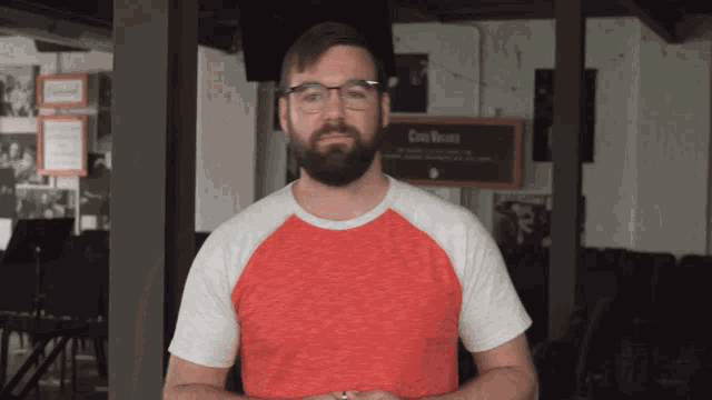 a man wearing glasses and a red and white shirt stands in front of a sign that says come values
