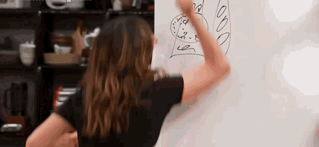 a woman is drawing on a whiteboard with her hand .