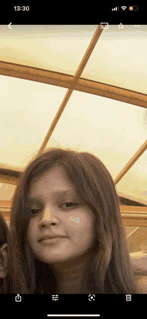 a girl 's face is displayed on a phone screen with the time 13:30