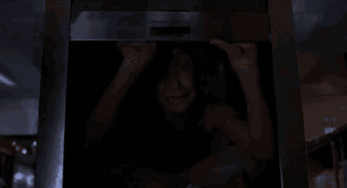 a woman is screaming in a dark room while standing in an elevator .