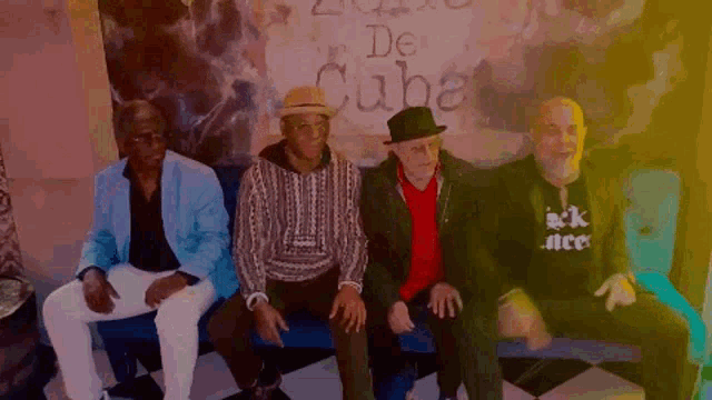 a group of men are sitting in front of a sign that says de cuba