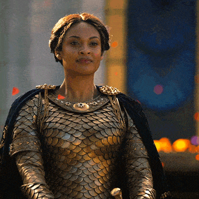 a woman wearing armor and a cape is standing in front of a clock