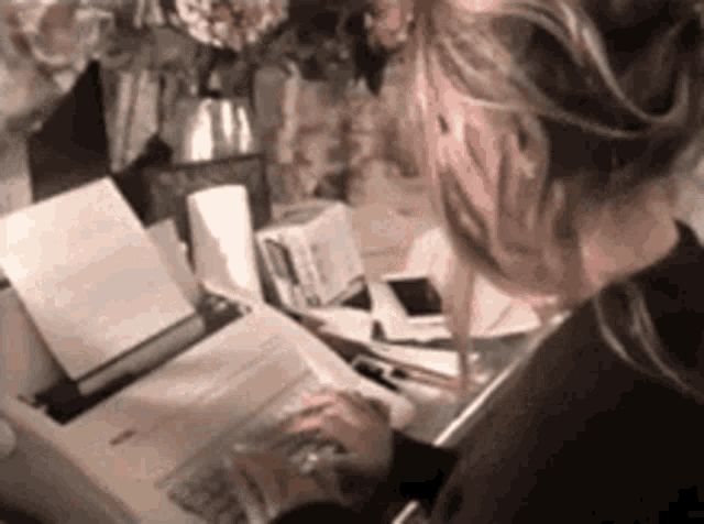 a woman is sitting at a desk reading a book