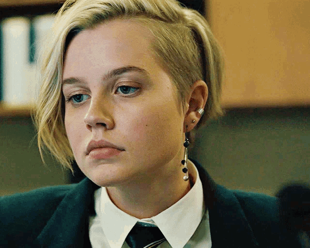 a close up of a woman 's face wearing earrings and a tie