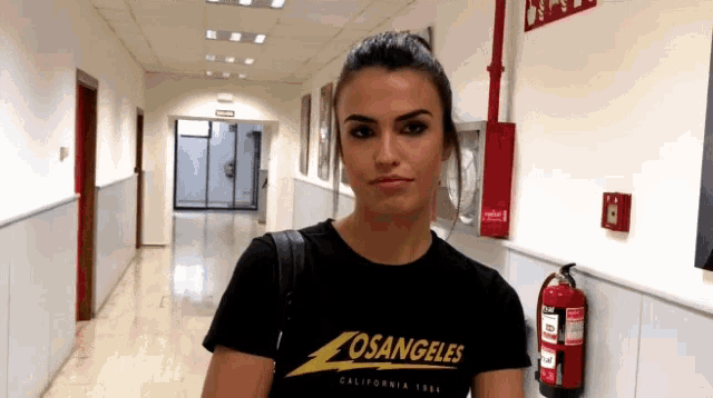a woman is wearing a losangeles t-shirt in a hallway