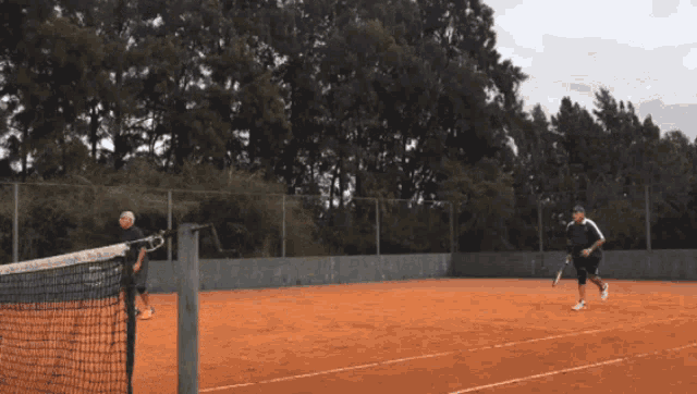two men playing tennis on a clay court