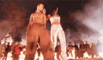 a man and a woman are dancing in front of a crowd of people in front of a fire .