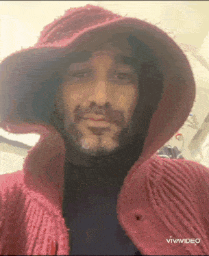 a man with a beard wearing a red hat and a sweater